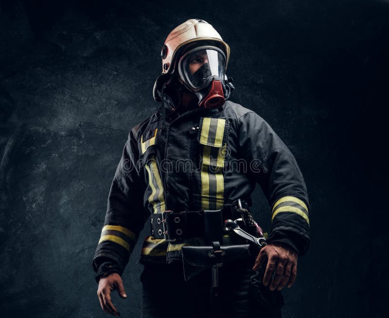 Portret van een mannetje in het volledige brandbestrijdersmateriaal stellen in een donkere studio
