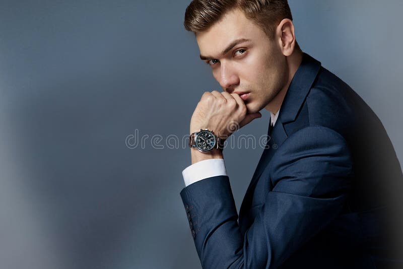 Portret van een mensenzitting met een kostuum met een horloge, studio royalty-vrije stock afbeeldingen Portret van een mensenzitting met een kostuum met een horloge, studio royalty-vrije stock afbeeldingen