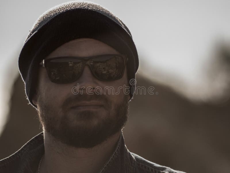 Portret van een modieuze mens met een baard in een gebreide hoed en zonnebril royalty-vrije stock foto's Portret van een modieuze mens met een baard in een gebreide hoed en zonnebril royalty-vrije stock foto's