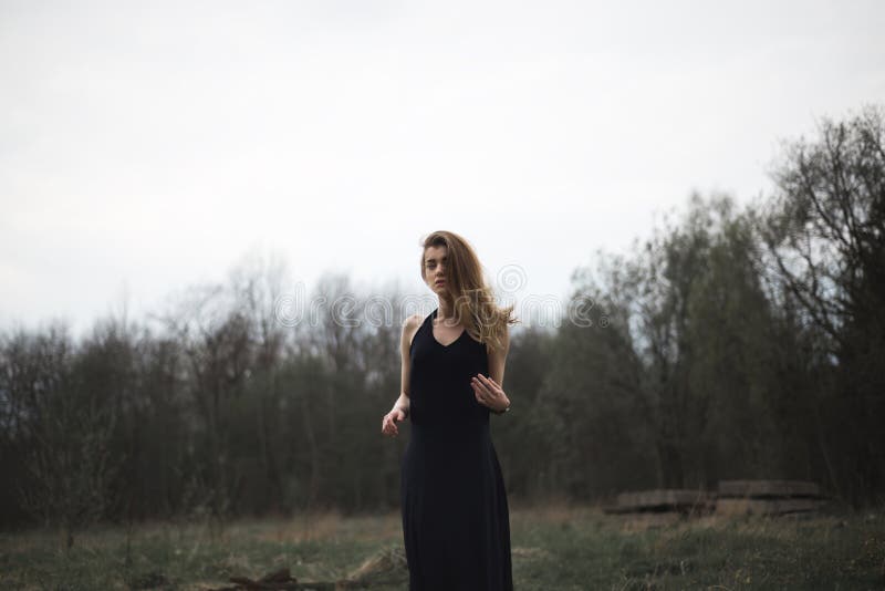 Portret van een mooi meisje in een zwarte laag op de aard stock foto Portret van een mooi meisje in een zwarte laag op de aard stock foto