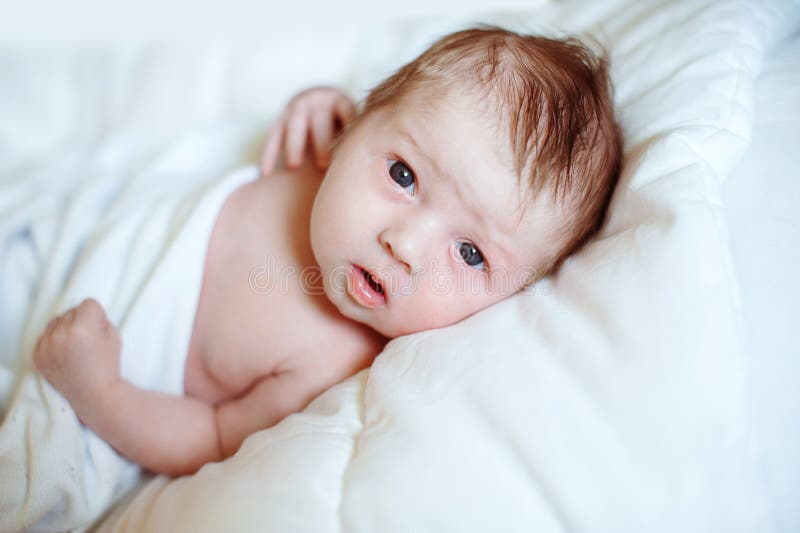Portret van een pasgeboren baby die de camera op een wit bed onderzoeken royalty-vrije stock foto Portret van een pasgeboren baby die de camera op een wit bed onderzoeken royalty-vrije stock foto