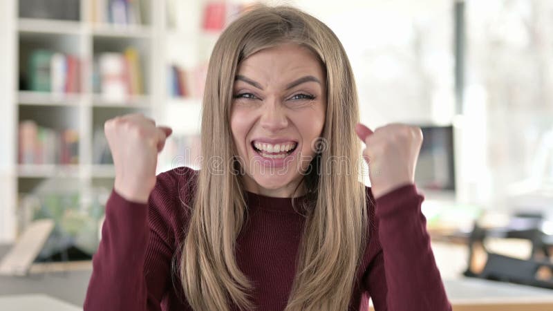 Portret van een positieve jonge vrouw die het succes van de vreugde viert