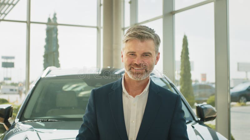 Portret van een rijpe , rijpe beard grijze haren man in een pak met smartphone die op de auto leunt en denkt of