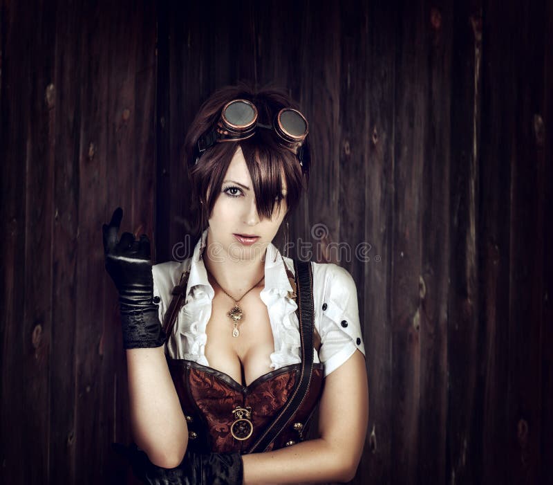 Portrait of a steampunk woman with big breast wearing vintage corset and retro goggles on old wooden background. Portrait of a steampunk woman with big breast wearing vintage corset and retro goggles on old wooden background