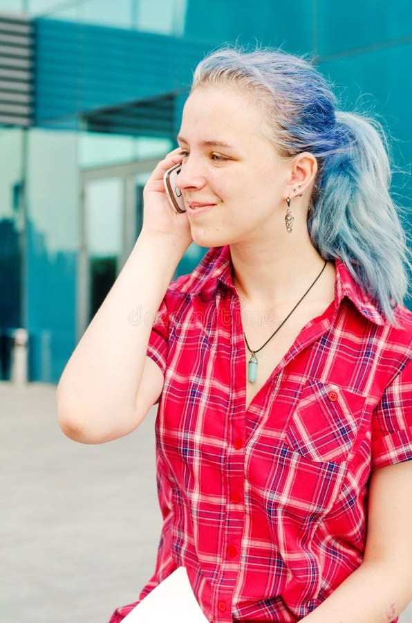 Portret van een toevallig leuk en jong meisje met blauw haar in de stad die op de telefoon spreken stock afbeeldingen Portret van een toevallig leuk en jong meisje met blauw haar in de stad die op de telefoon spreken stock afbeeldingen
