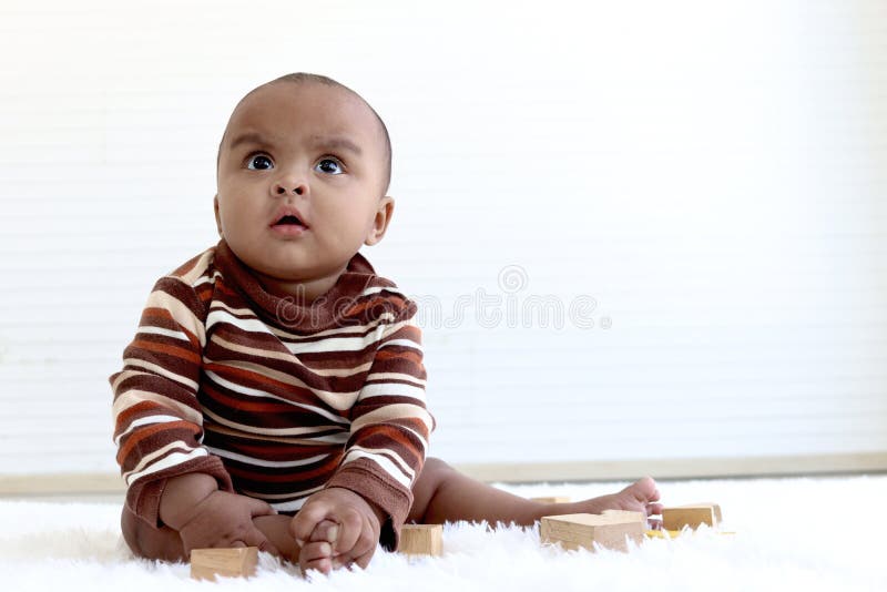 Portrait of adorable six month crawling African American baby playing with wooden developmental toys on fluffy white rug, happy sweet little girl kid learning, childhood and baby care concept. Portrait of adorable six month crawling African American baby playing with wooden developmental toys on fluffy white rug, happy sweet little girl kid learning, childhood and baby care concept