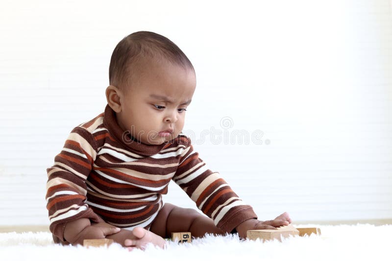 Portrait of adorable six month crawling African American baby playing with wooden developmental toys on fluffy white rug, happy sweet little girl kid learning, childhood and baby care concept. Portrait of adorable six month crawling African American baby playing with wooden developmental toys on fluffy white rug, happy sweet little girl kid learning, childhood and baby care concept