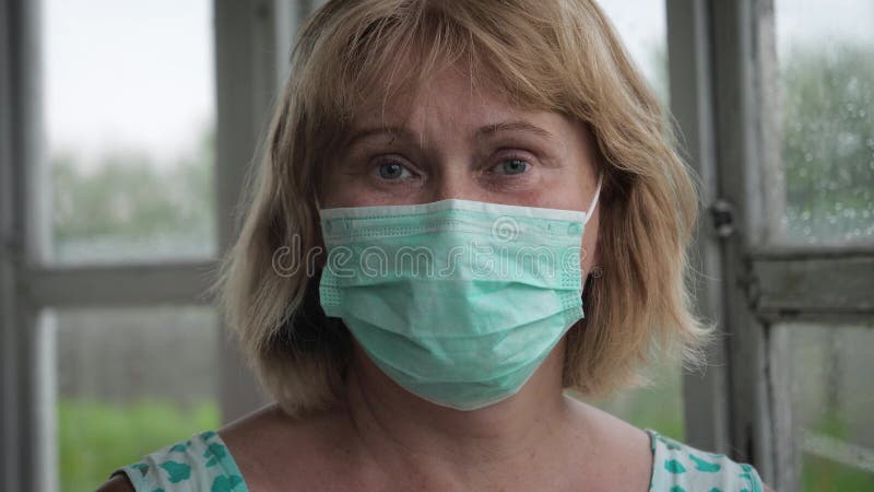 Portret van een volwassen kaukasische vrouw in een beschermend medisch masker op zelfisolatie