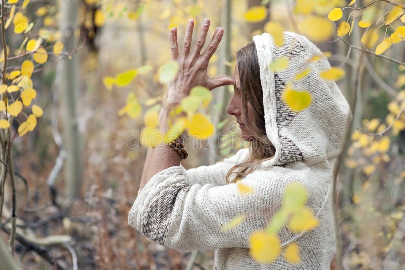 Portrait of a beautiful middle aged woman practicing  spiritual yoga meditation outdoors in the autumn woods with her hands focused on her third eye. . Portrait of a beautiful middle aged woman practicing  spiritual yoga meditation outdoors in the autumn woods with her hands focused on her third eye.