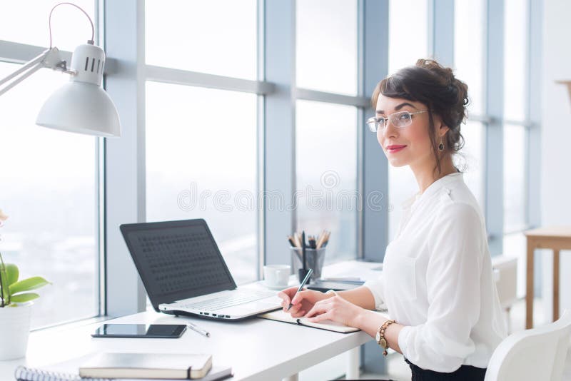 Portret van een vrouwelijke schrijver die op kantoor werken, die laptop met behulp van, die glazen dragen Jonge werknemer die haa royalty-vrije stock foto Portret van een vrouwelijke schrijver die op kantoor werken, die laptop met behulp van, die glazen dragen Jonge werknemer die haa royalty-vrije stock foto
