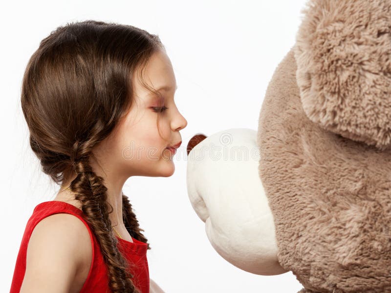 Portret van een weinig donkerbruin meisje die een teddybeer kussen in it royalty-vrije stock afbeeldingen Portret van een weinig donkerbruin meisje die een teddybeer kussen in it royalty-vrije stock afbeeldingen