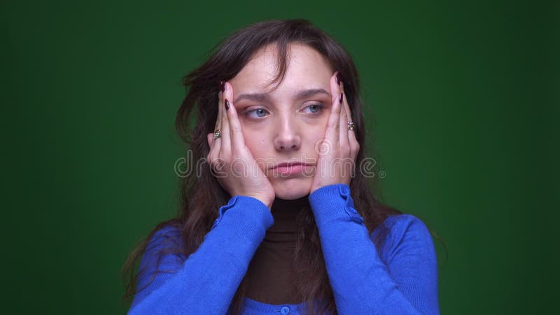 Portret van gedeprimeerde donkerbruine onderneemster die aan migraine op groene achtergrond lijden