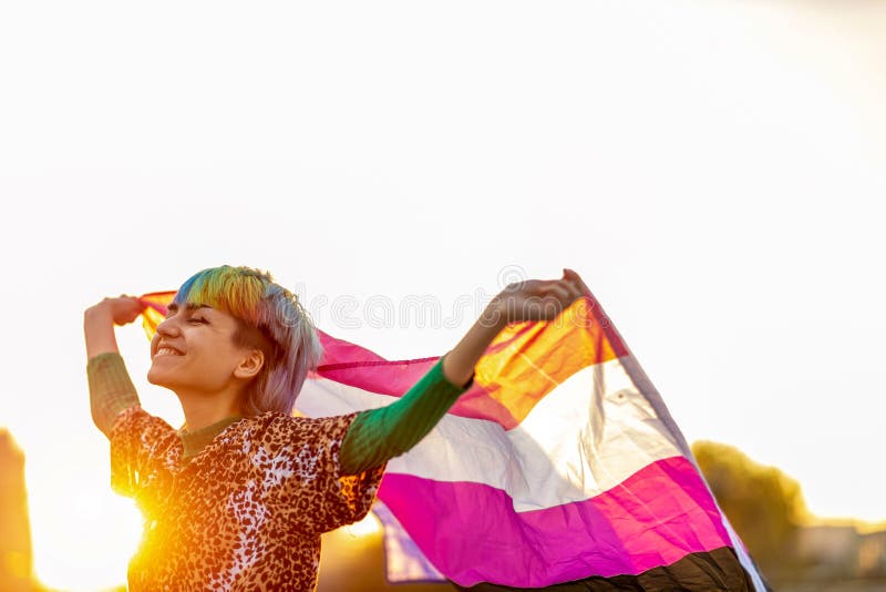 Portret van gelukkige niet binaire persoon die de vlag van een geslachtsorgaan zwaait