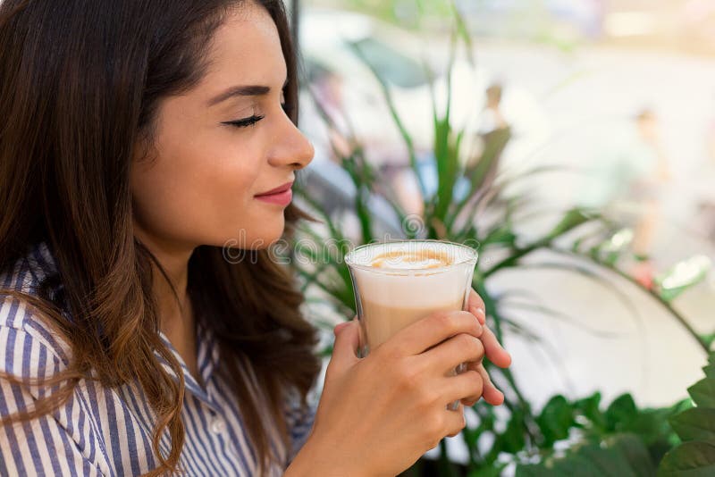 Portret van glimlachende jonge vrouw die ochtend van koffie in koffie genieten royalty-vrije stock fotografie Portret van glimlachende jonge vrouw die ochtend van koffie in koffie genieten royalty-vrije stock fotografie