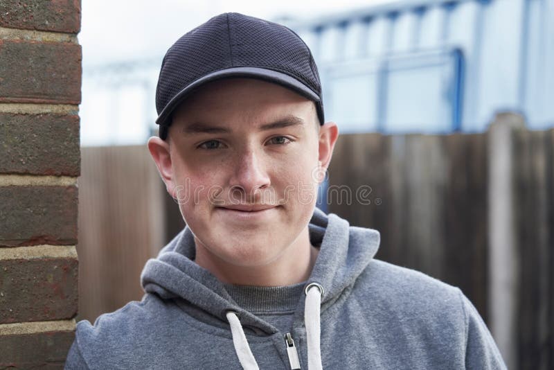 Portret van Glimlachende Tiener die tegen Muur in het Stedelijke Plaatsen leunen stock foto's Portret van Glimlachende Tiener die tegen Muur in het Stedelijke Plaatsen leunen stock foto's