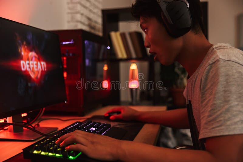 Portret van het Aziatische tienergamerjongen verliezen terwijl het spelen van videog stock afbeelding Portret van het Aziatische tienergamerjongen verliezen terwijl het spelen van videog stock afbeelding