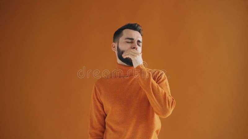 Portret van het bored hipster kijken rond geeuw die zich op oranje achtergrond bevinden