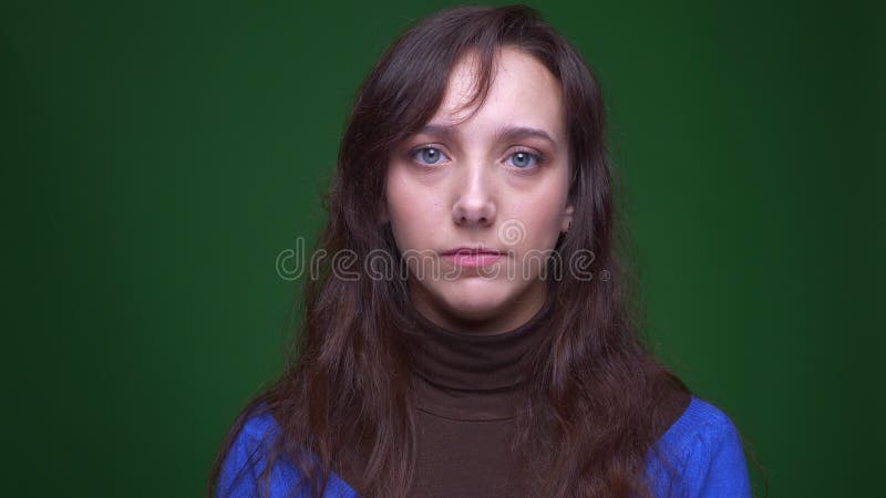 Portret van het gedeprimeerde donkerbruine onderneemster letten droevig op in camera op groene achtergrond