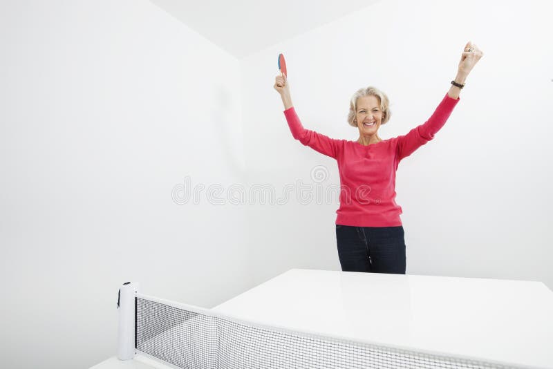 Portret van hogere vrouwelijke pingpongspeler met wapens opgeheven het vieren overwinning royalty-vrije stock foto Portret van hogere vrouwelijke pingpongspeler met wapens opgeheven het vieren overwinning royalty-vrije stock foto