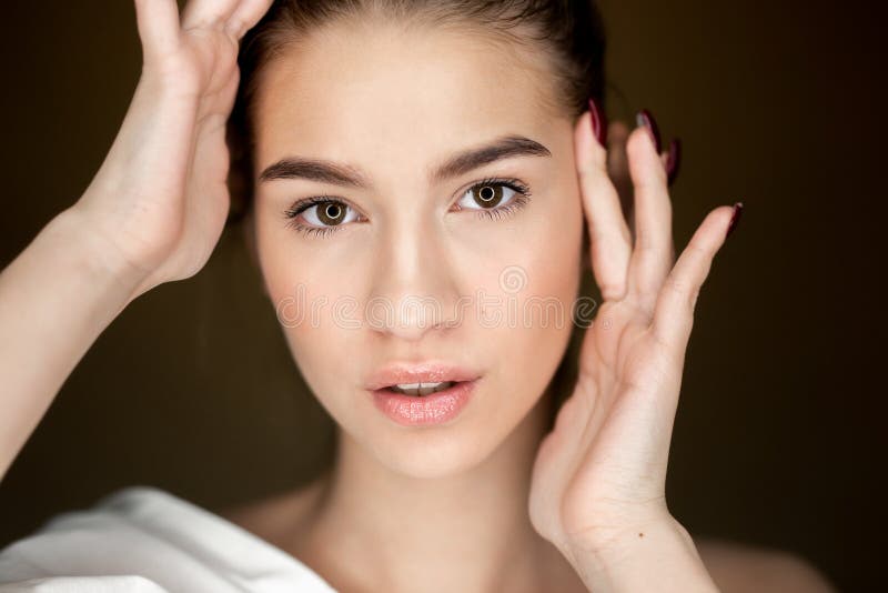 Portret van jong mooi meisje die met natuurlijke make-up haar handen op haar hoofd houden stock fotografie Portret van jong mooi meisje die met natuurlijke make-up haar handen op haar hoofd houden stock fotografie
