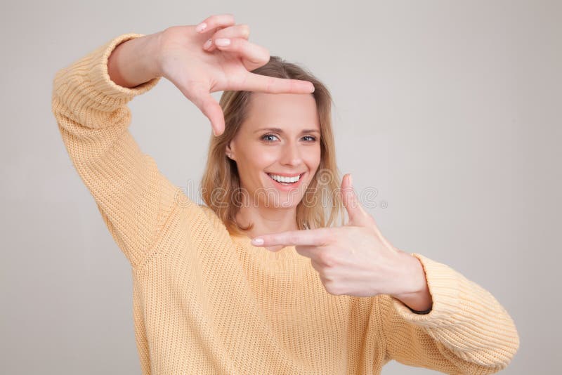 Portret van jonge blondevrouw met vrolijke gelukkige uitdrukking op haar gezicht, met goede stemming, die vierkant met haar vinge royalty-vrije stock afbeelding Portret van jonge blondevrouw met vrolijke gelukkige uitdrukking op haar gezicht, met goede stemming, die vierkant met haar vinge royalty-vrije stock afbeelding