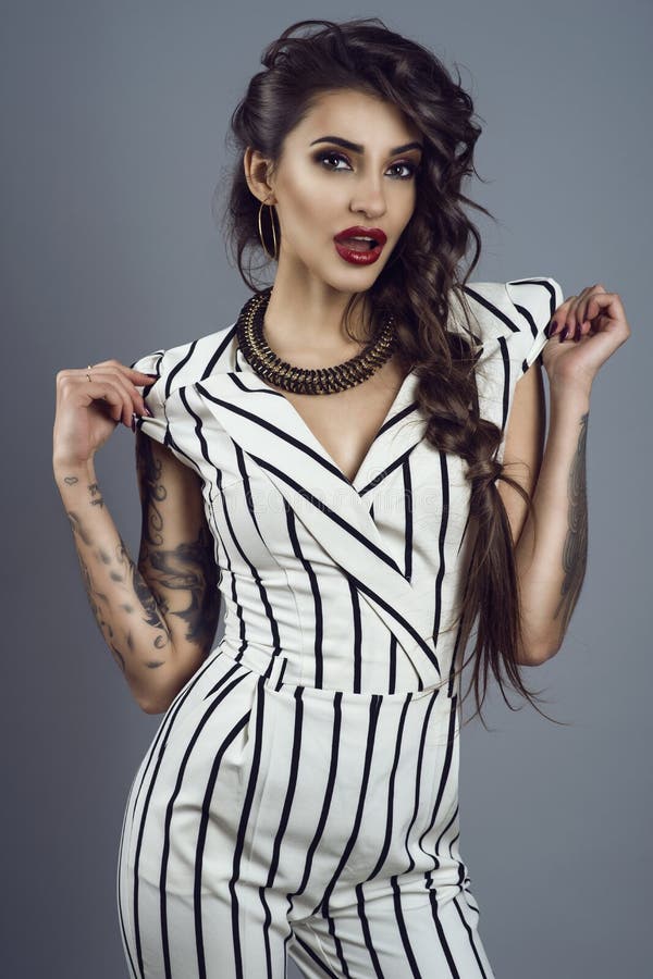 Portret van jonge schitterende donker-haired getatoeeerde dame in de gestreepte algemene en schitterende kokers van de halsbandho royalty-vrije stock fotografie Portret van jonge schitterende donker-haired getatoeeerde dame in de gestreepte algemene en schitterende kokers van de halsbandho royalty-vrije stock fotografie