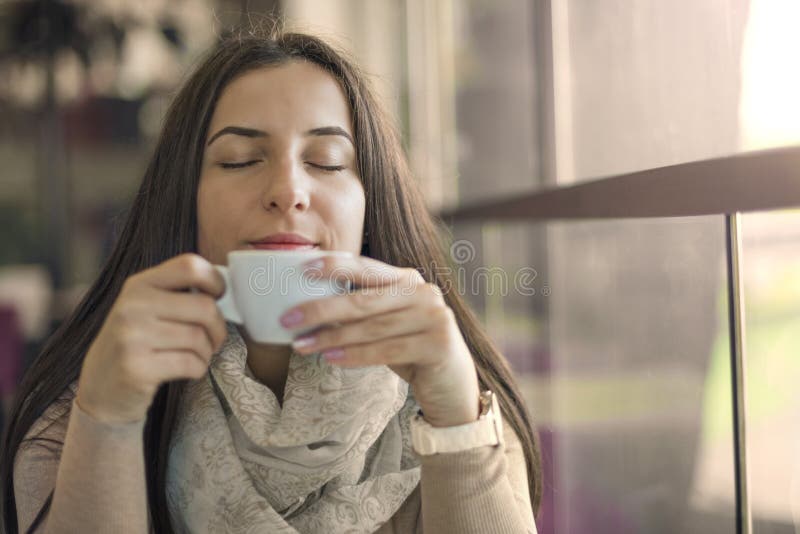 Portret van jonge schitterende vrouwelijke het drinken kop van koffie en het genieten van van haar alleen vrije tijd stock foto Portret van jonge schitterende vrouwelijke het drinken kop van koffie en het genieten van van haar alleen vrije tijd stock foto