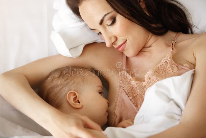 Portret van jonge tedere moeder die haar baby de borst geven die in bed thuis liggen Van hierboven royalty-vrije stock afbeeldingen Portret van jonge tedere moeder die haar baby de borst geven die in bed thuis liggen Van hierboven royalty-vrije stock afbeeldingen