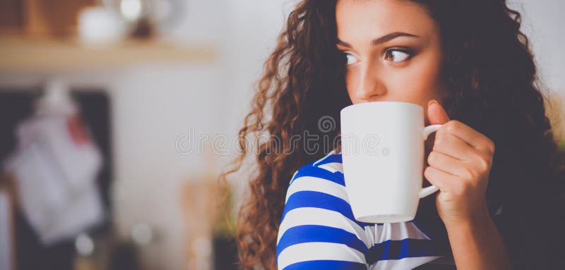 Portret van jonge vrouw met kop tegen keuken binnenlandse achtergrond royalty-vrije stock foto Portret van jonge vrouw met kop tegen keuken binnenlandse achtergrond royalty-vrije stock foto
