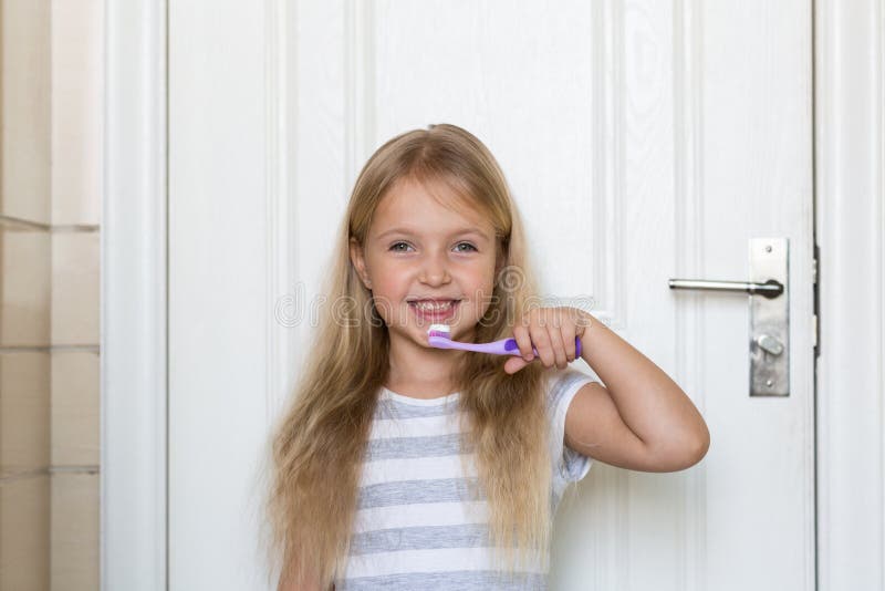 Portret van leuk meisje met blondehaar dat schoonmakende tand met borstel en tandpasta in badkamers royalty-vrije stock foto Portret van leuk meisje met blondehaar dat schoonmakende tand met borstel en tandpasta in badkamers royalty-vrije stock foto
