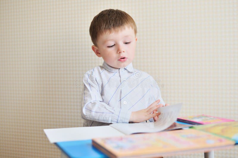 Portret van leuke jongen met pen en document bij bureau in klaslokaal royalty-vrije stock foto's Portret van leuke jongen met pen en document bij bureau in klaslokaal royalty-vrije stock foto's