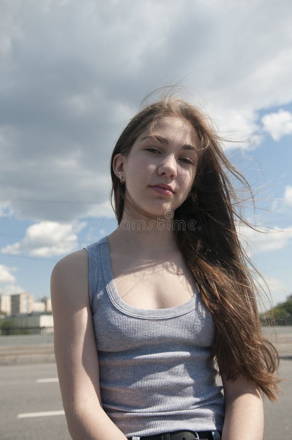 Portret van mooi jong meisje met blazend haar in wind op de achtergrond van de stads blauwe hemel stock afbeeldingen Portret van mooi jong meisje met blazend haar in wind op de achtergrond van de stads blauwe hemel stock afbeeldingen