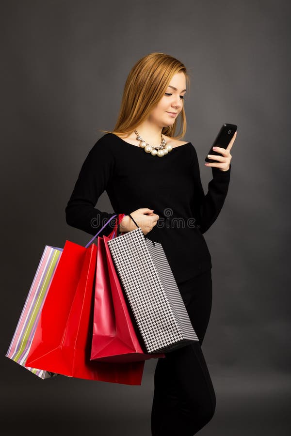 Portret van mooi meisje met het winkelen zakken die berichten controleren stock foto Portret van mooi meisje met het winkelen zakken die berichten controleren stock foto