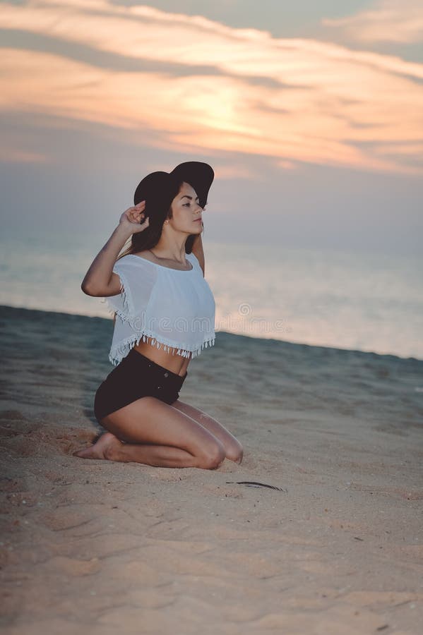 Portret van mooie gelukkige vrouw in hoed en borrels die van de achtergrond van het zonsondergangstrand genieten stock foto's Portret van mooie gelukkige vrouw in hoed en borrels die van de achtergrond van het zonsondergangstrand genieten stock foto's
