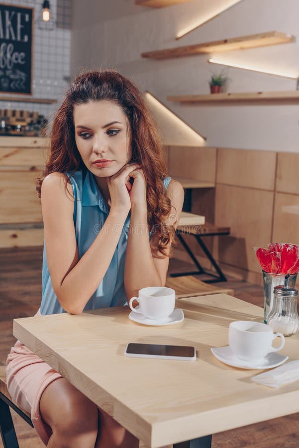 portret van nadenkende vrouwenzitting alleen bij lijst met koppen van koffie royalty-vrije stock afbeelding portret van nadenkende vrouwenzitting alleen bij lijst met koppen van koffie royalty-vrije stock afbeelding