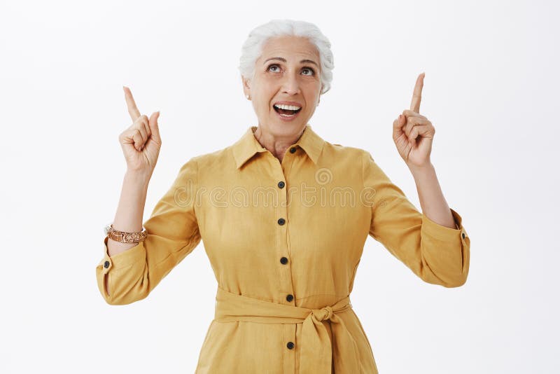 Portret van tevreden onbezorgde gezonde oude dame die in in gele laag van groot weer genieten die handen opheffen die eruit zien stock foto Portret van tevreden onbezorgde gezonde oude dame die in in gele laag van groot weer genieten die handen opheffen die eruit zien stock foto