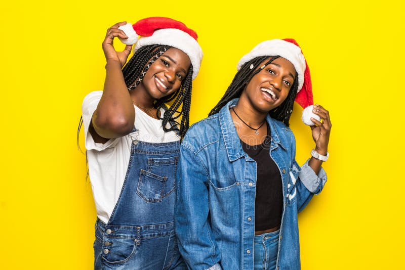 Portret van twee jonge afrikaanse vrouwen met kerstmantel op gele achtergrond stock fotografie Portret van twee jonge afrikaanse vrouwen met kerstmantel op gele achtergrond stock fotografie