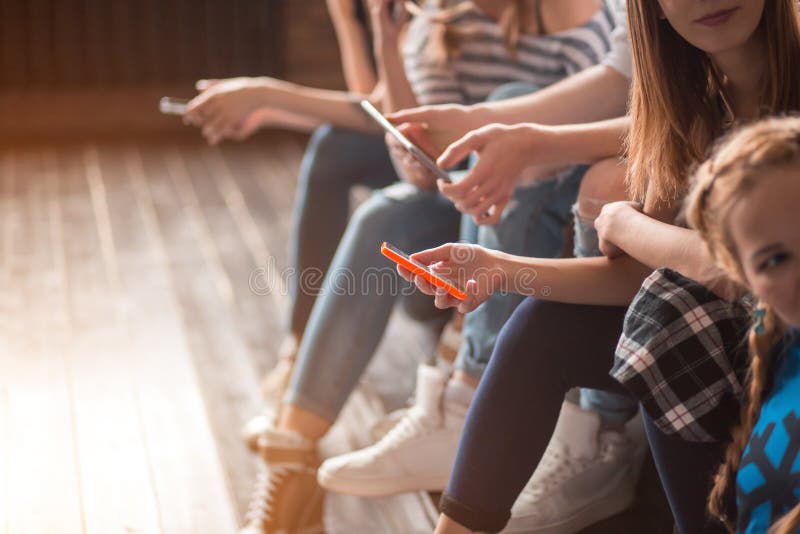 Portret van vrolijke jonge vrienden die slimme telefoon bekijken terwijl het zitten in koffie royalty-vrije stock afbeelding Portret van vrolijke jonge vrienden die slimme telefoon bekijken terwijl het zitten in koffie royalty-vrije stock afbeelding
