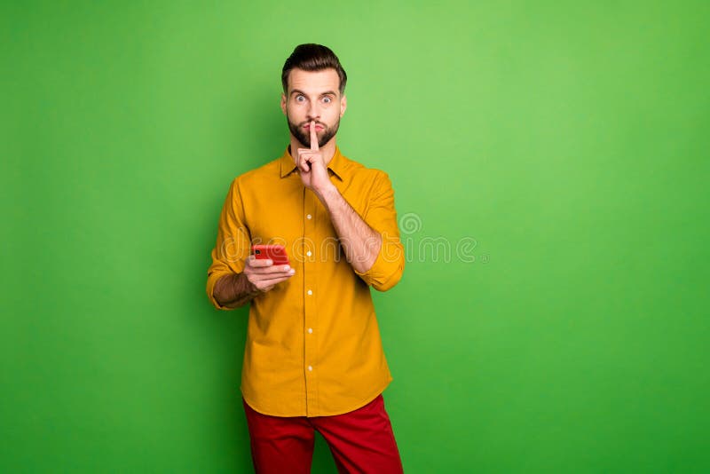 Portrait of his he nice attractive funky, funny mysterious guy in formal shirt holding in hand cell showing shh sign isolated on bright vivid shine vibrant green color background. Portrait of his he nice attractive funky, funny mysterious guy in formal shirt holding in hand cell showing shh sign isolated on bright vivid shine vibrant green color background