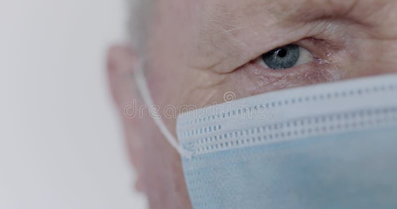 Portret van één gezichtsdeel van de blueyed senior man in een medisch masker op de achtergrond