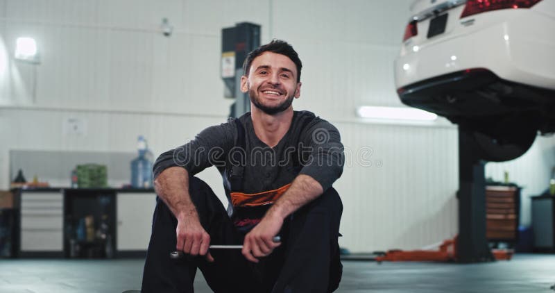 Portret w mechaniku garażowym, w mundurze, uśmiechający się duży i patrzący prosto do kamery przed rozpoczęciem pracy