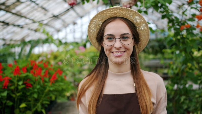 Portret wesołego młodego rolnika, który nosi pudełko warzyw w lekkiej szklarni