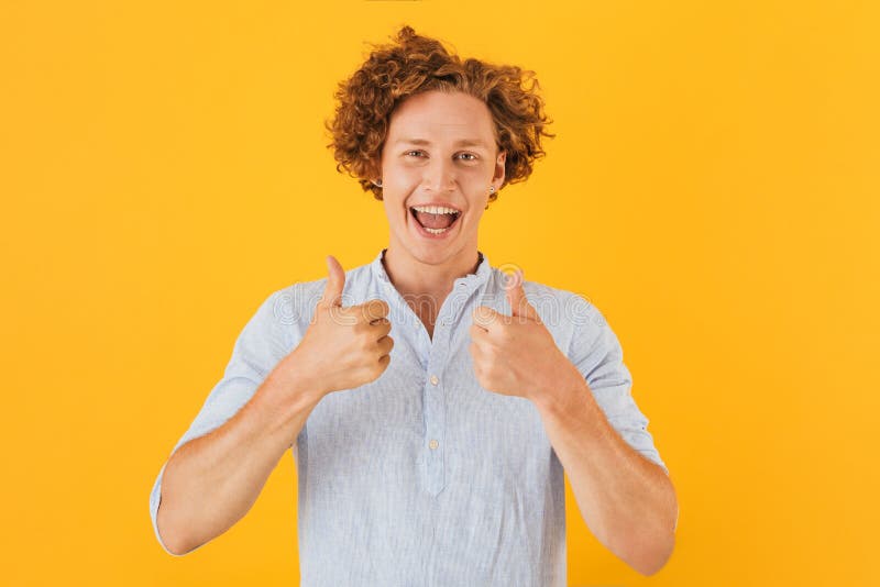 Portret z podnieceniem przystojny facet 20s uśmiecha się kciuki i pokazuje zdjęcie stock Portret z podnieceniem przystojny facet 20s uśmiecha się kciuki i pokazuje zdjęcie stock
