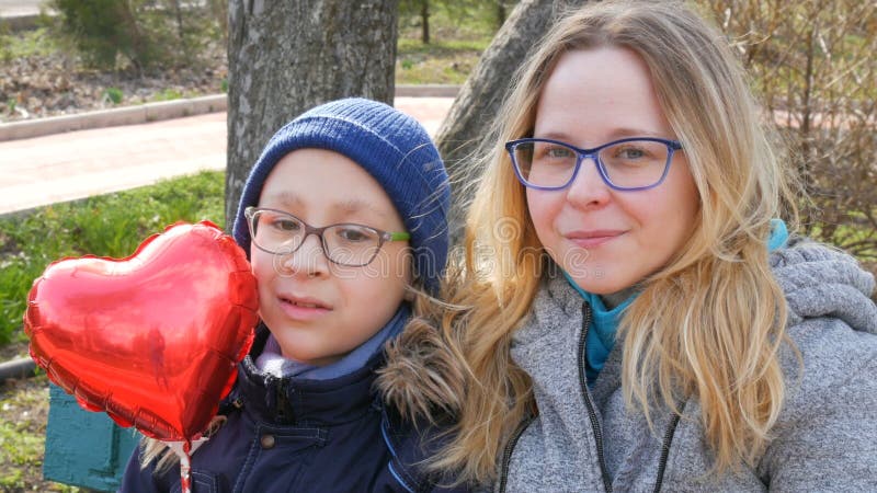 Portret zabawnej matki i jej chłopca, nastolatka w okularach uśmiechających się wiosną w parku. dzień matki