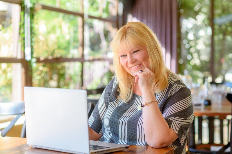 Portreta elegancki w średnim wieku plus wielkościowy bizneswoman pracuje na laptopie w kreatywnie kawiarni lub biurze obrazy stock Portreta elegancki w średnim wieku plus wielkościowy bizneswoman pracuje na laptopie w kreatywnie kawiarni lub biurze obrazy stock