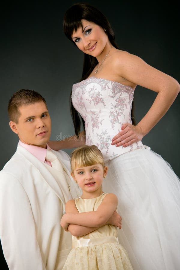 Portrait of wedding couple and little girl bridesmaid. Bride wearing romantic white wedding dress, groom in white suit. Portrait of wedding couple and little girl bridesmaid. Bride wearing romantic white wedding dress, groom in white suit.