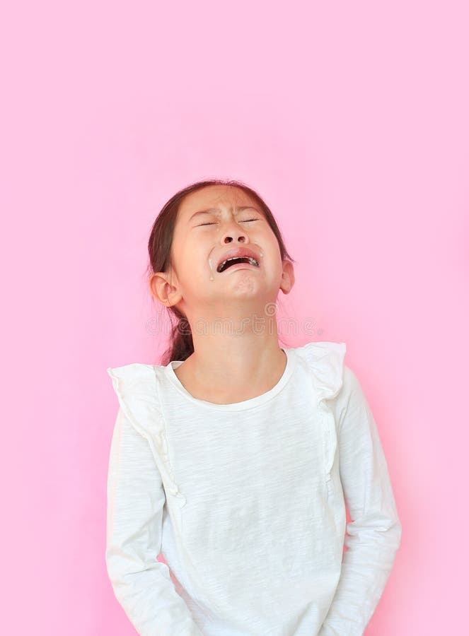 Portrait asian little girl crying isolated on pink background. Angry kid with sad expressions and screaming. Portrait asian little girl crying isolated on pink background. Angry kid with sad expressions and screaming.