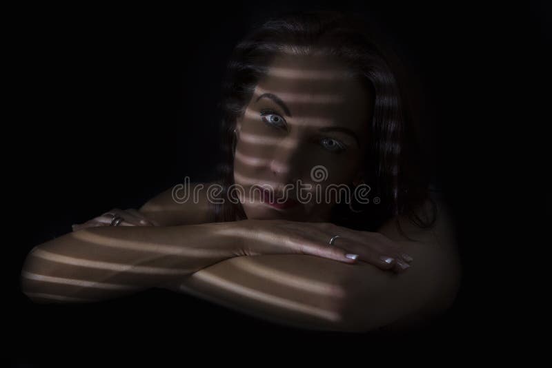 Portretul unei femei care stă în întuneric cu linii întunecate de bl stock photography