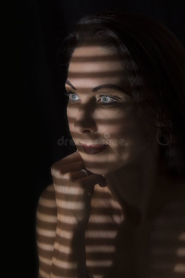 Portretul unei femei care stă în întuneric cu linii întunecate de bl royalty free stock photo