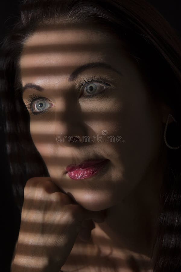 Portretul unei femei stând în întuneric cu linii întunecate de bl stock image